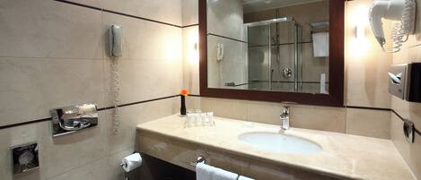 A modern bathroom with a large mirror, a sink, a toilet, and a shower.