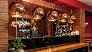 A bar area with wooden paneling, a polished bar counter, and multiple hanging spherical light fixtures. - Starhotels Ritz (Milan)