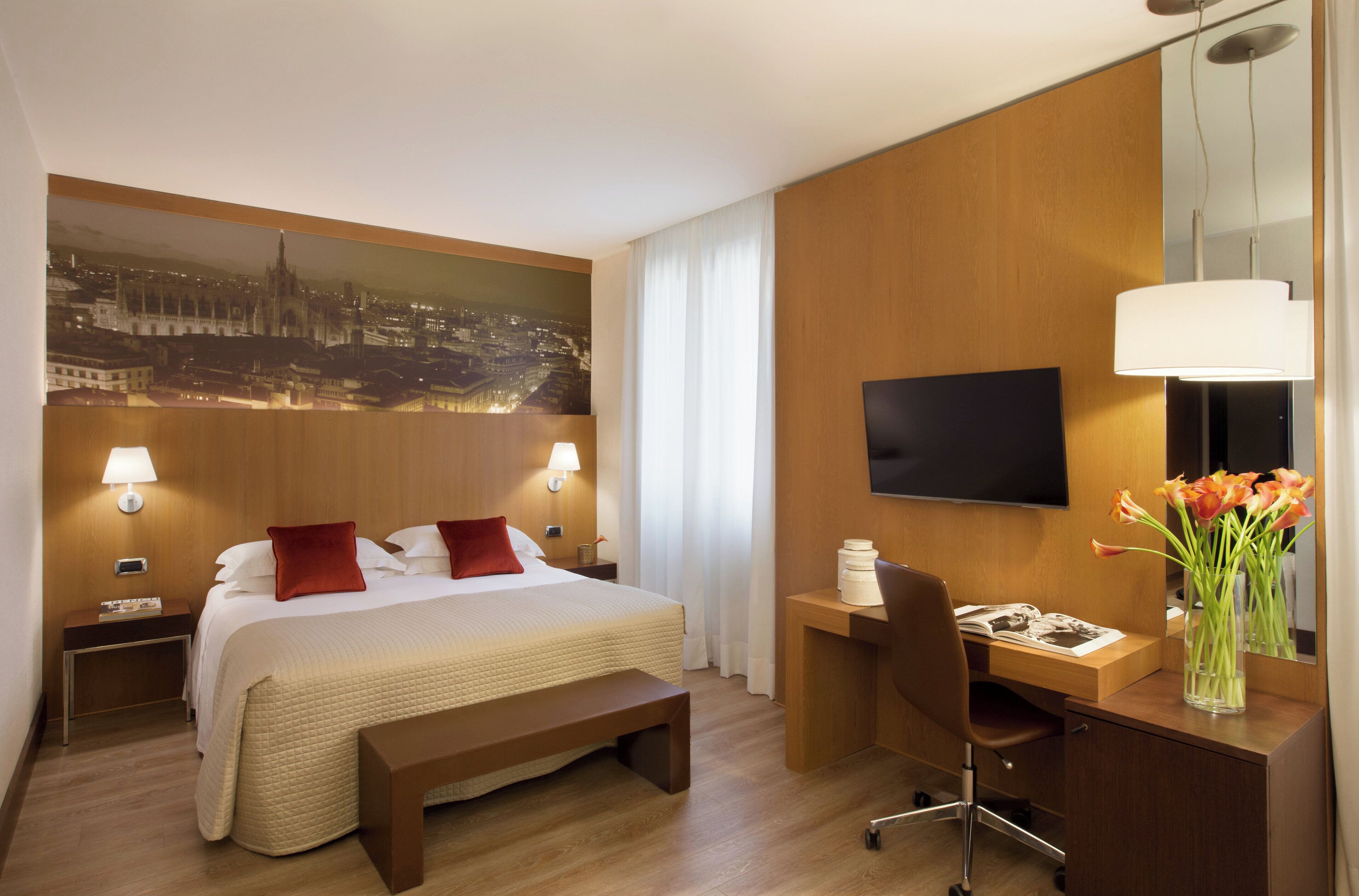 Une chambre d’hôtel avec un grand lit, un bureau, une chaise, une télévision et une vue sur le paysage urbain.