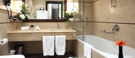 A modern bathroom with a large mirror, a bathtub, and a vanity with a sink and towel rack.