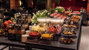 A buffet with various food items and a decorative plant. - Starhotels Ritz (Milan)