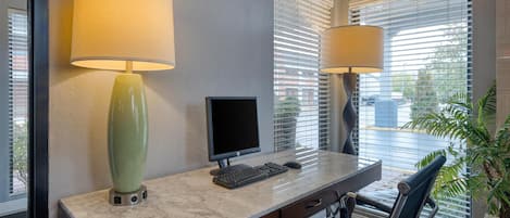 A modern office desk with a computer, two lamps, and a chair.