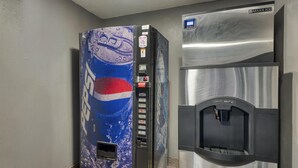 Máquina expendedora con logotipo de Pepsi y dispensador de agua adosado a un refrigerador de acero inoxidable.
