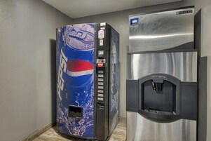 A vending machine with a Pepsi logo and a water dispenser attached to a stainless steel refrigerator.