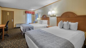 Habitación de hotel con dos camas, un escritorio, una silla y una ventana con cortinas.