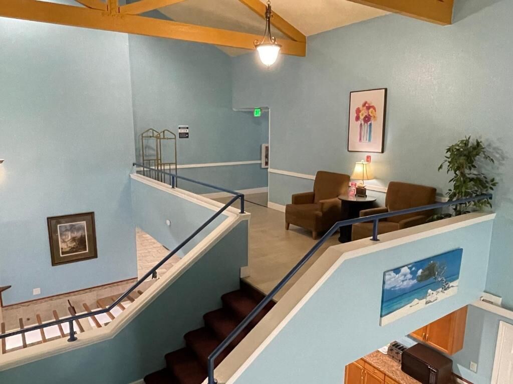 A multi-level interior with a staircase, seating area, and artwork on the walls.