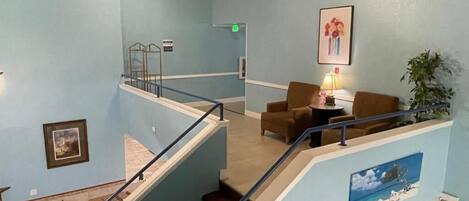 A multi-level interior with a staircase, seating area, and artwork on the walls.