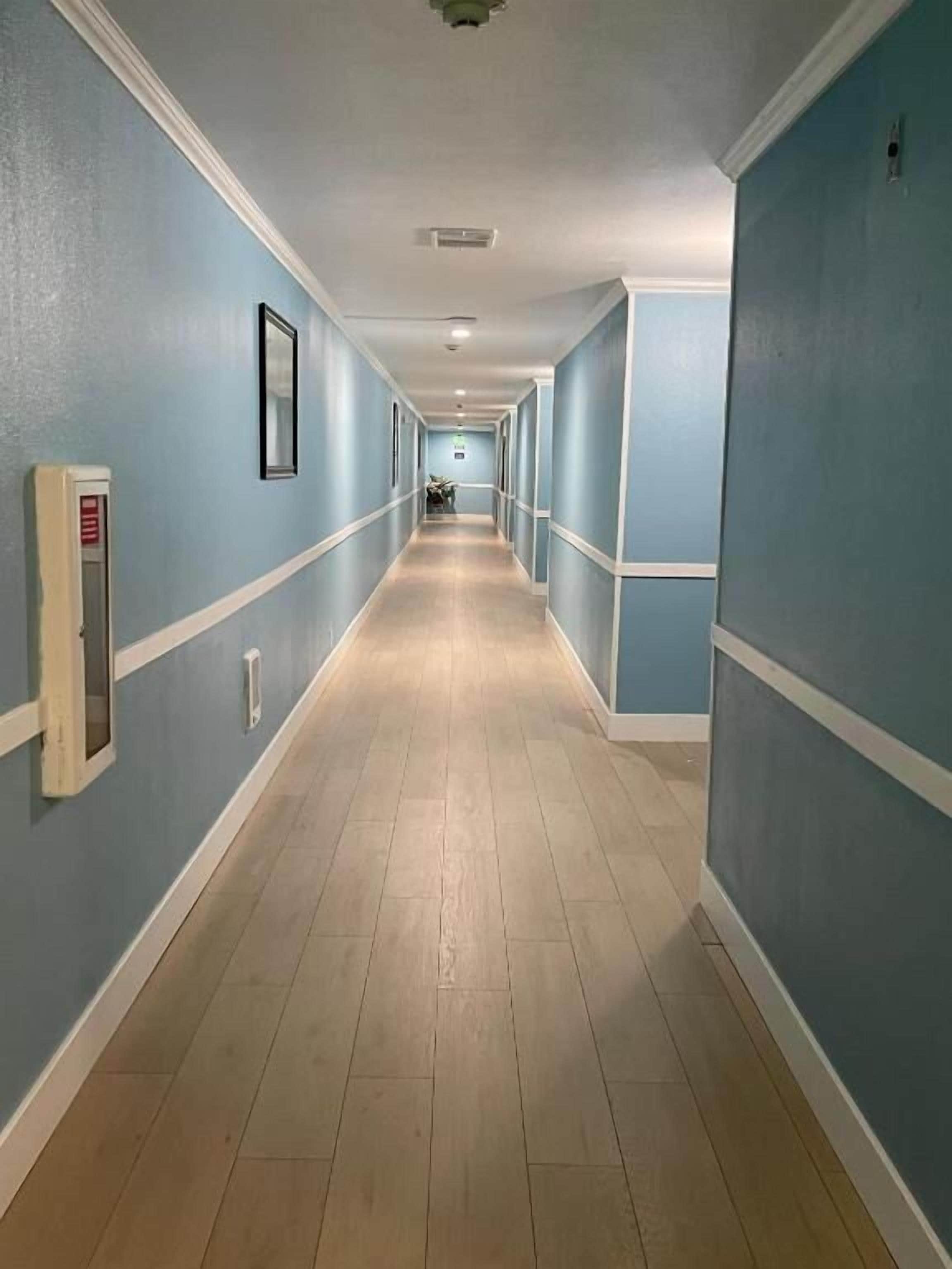 Un long couloir étroit aux murs bleu clair et au plancher en bois.