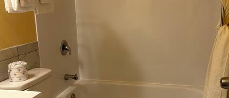 A bathroom with a toilet, sink, and bathtub. There are towels hanging on the wall and a shower curtain.
