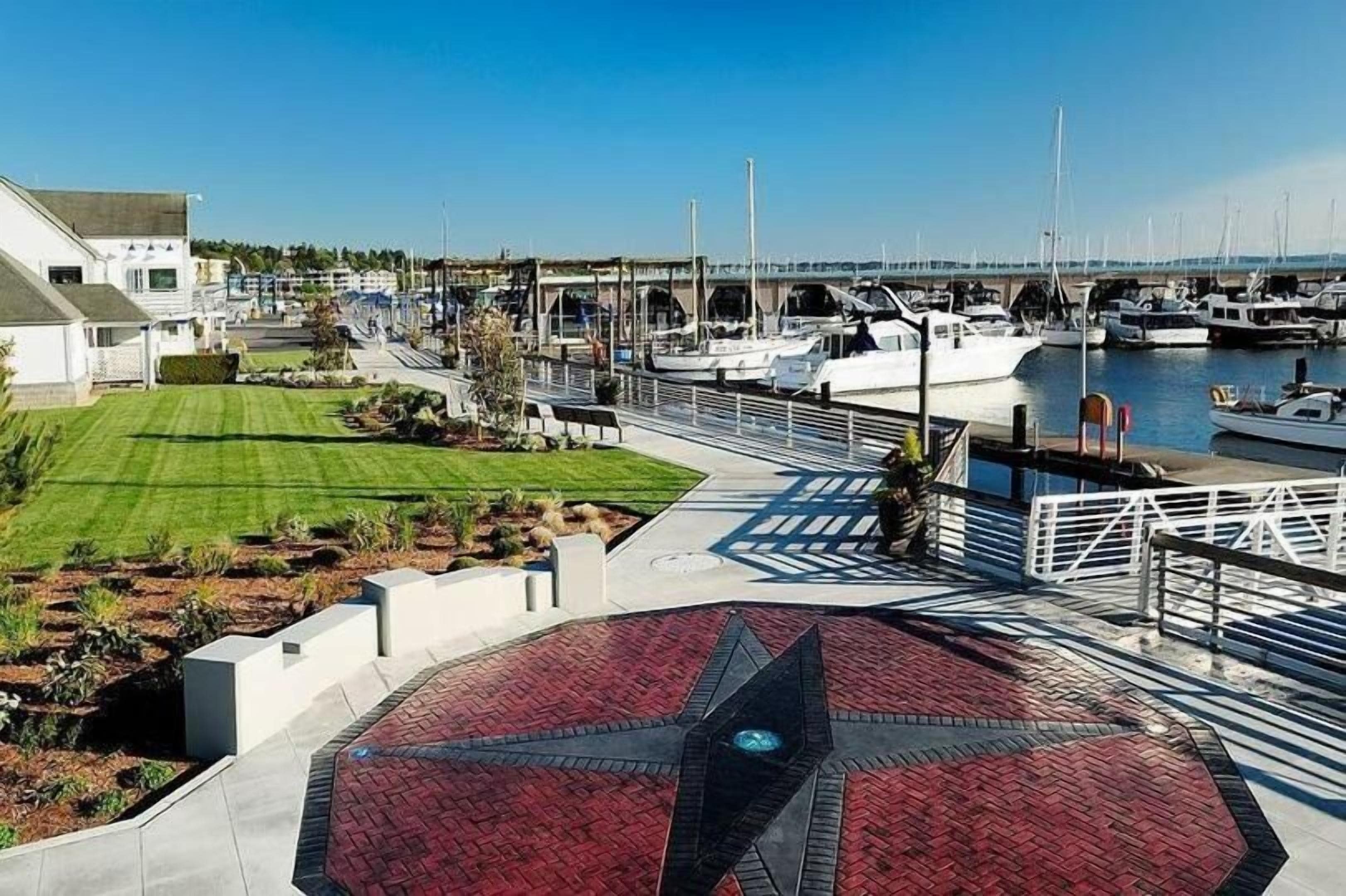 A marina with boats, a bridge, and a paved walkway with a geometric pattern.