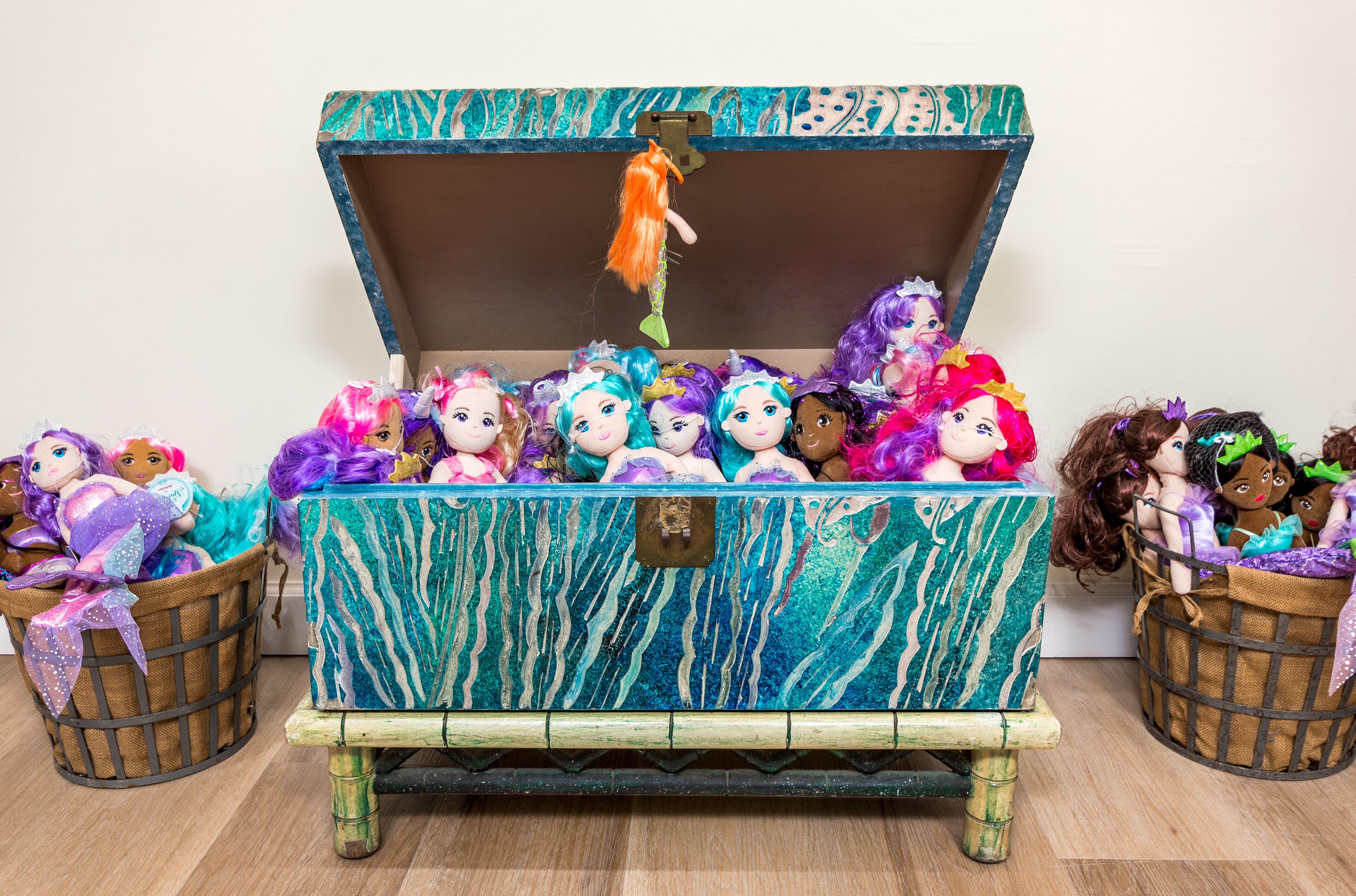 A large, open chest filled with colorful dolls and a mermaid doll hanging from the lid.