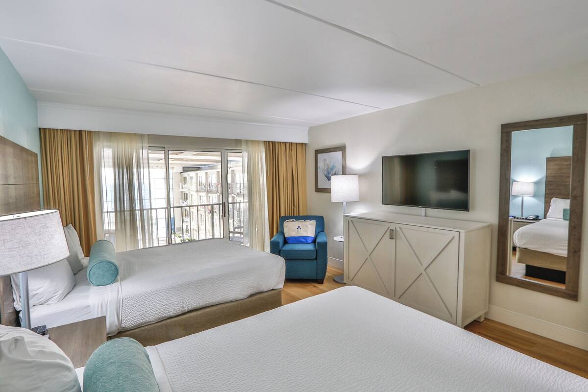 A hotel room with two beds, a TV, a desk, and a chair.