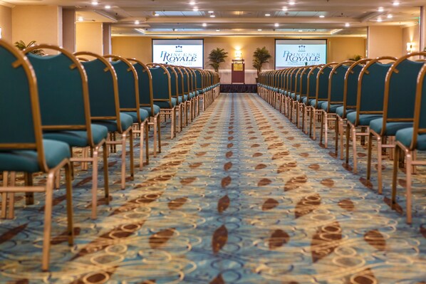 A conference room with rows of teal chairs and a patterned carpet.