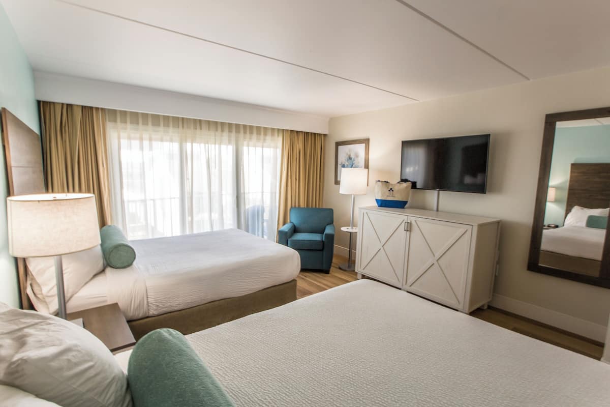 A hotel room with two beds, a TV, a desk, and a chair.