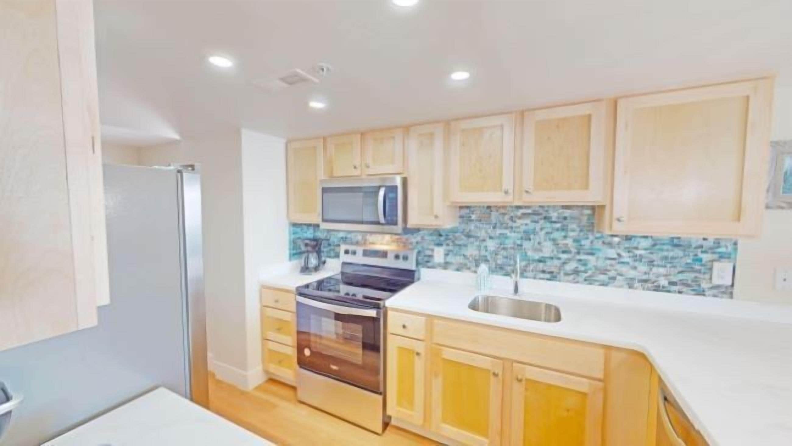 A modern kitchen with wooden cabinets, a stainless steel sink, a microwave, and an oven.