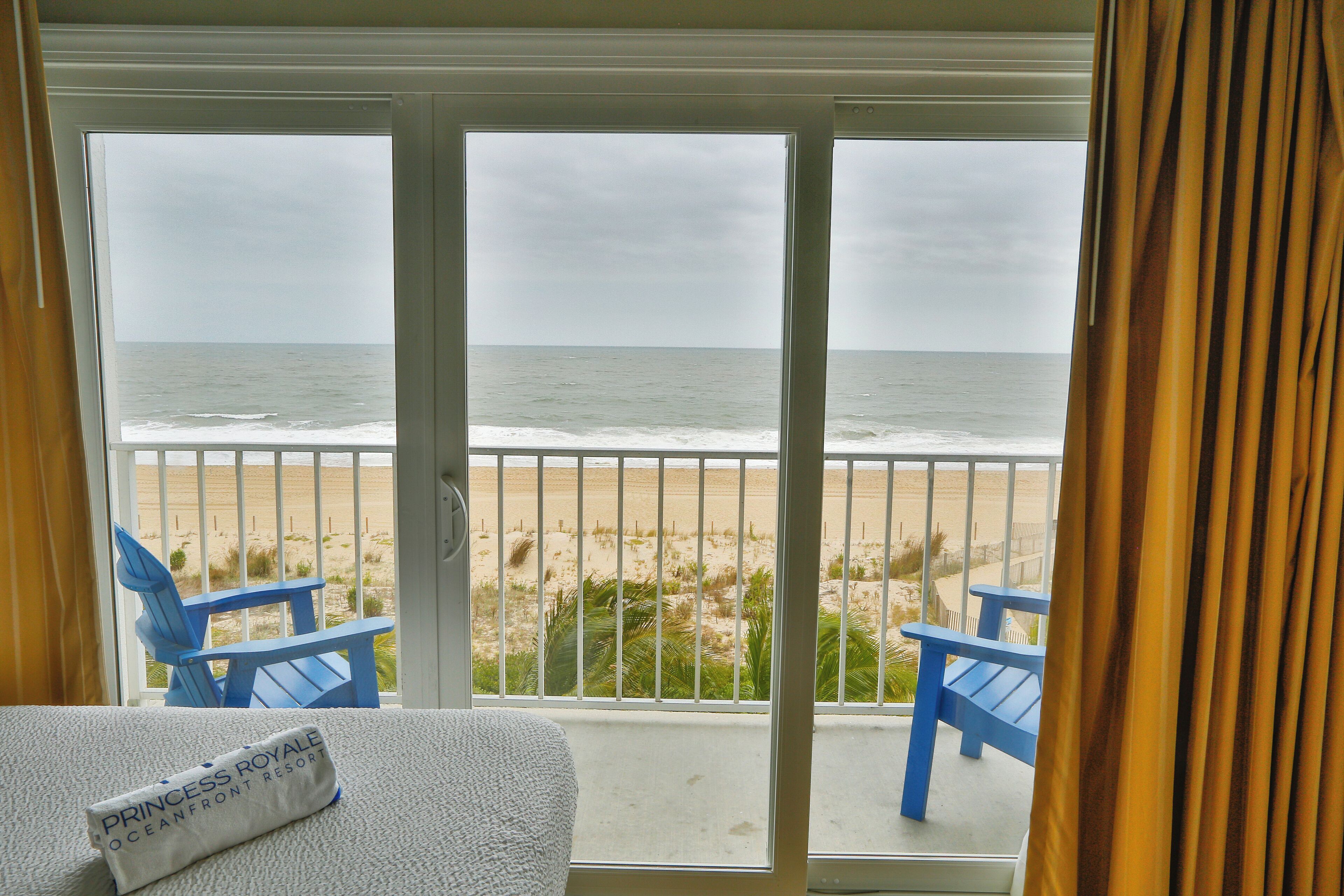 Habitación con vista a la playa, que incluye una cama con almohada blanca y un letrero que dice "Princess Royale Oceanfront Resort".