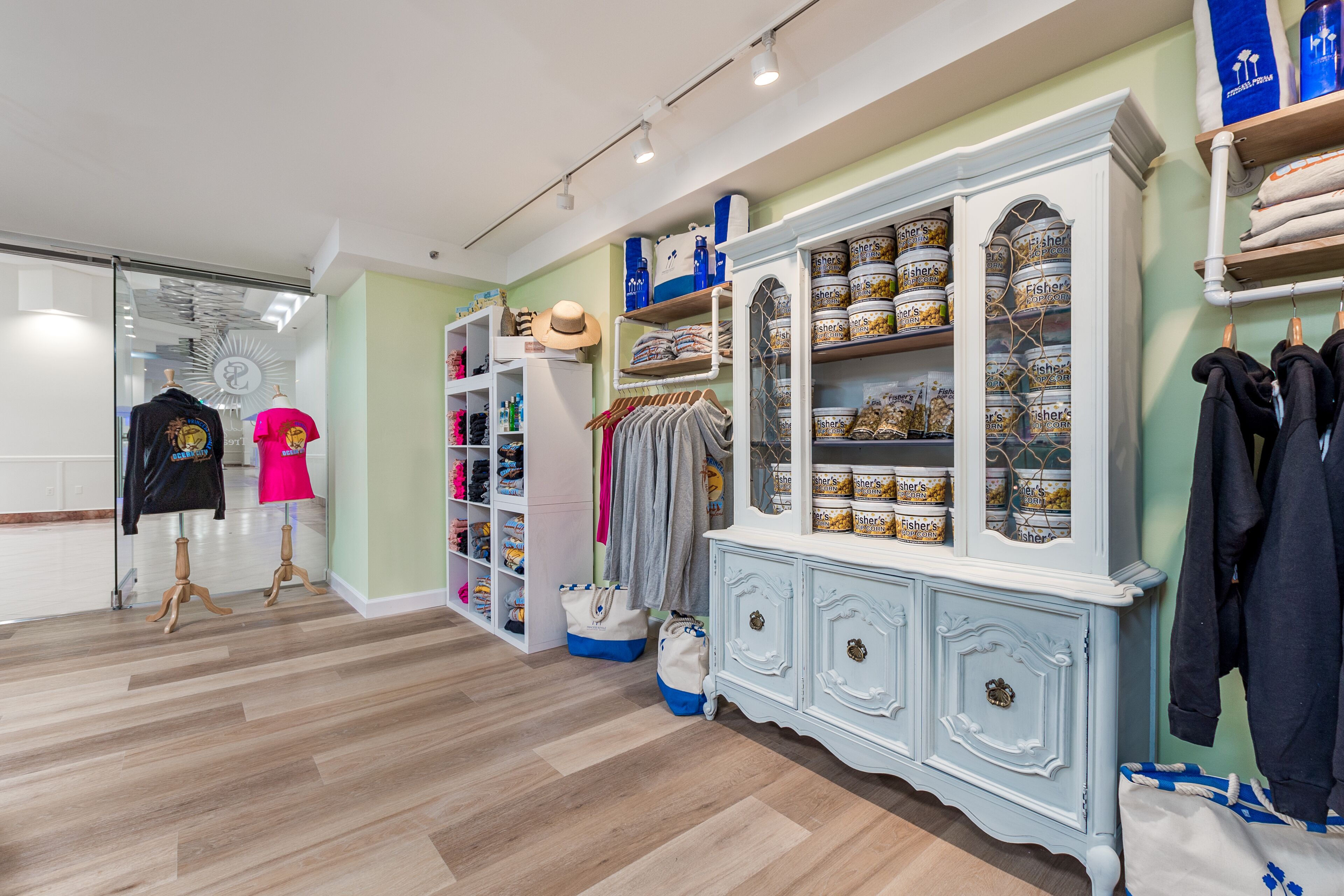 L’intérieur d’un hôtel-boutique présente un parquet en bois, un meuble blanc avec des rangements et un portant à vêtements.