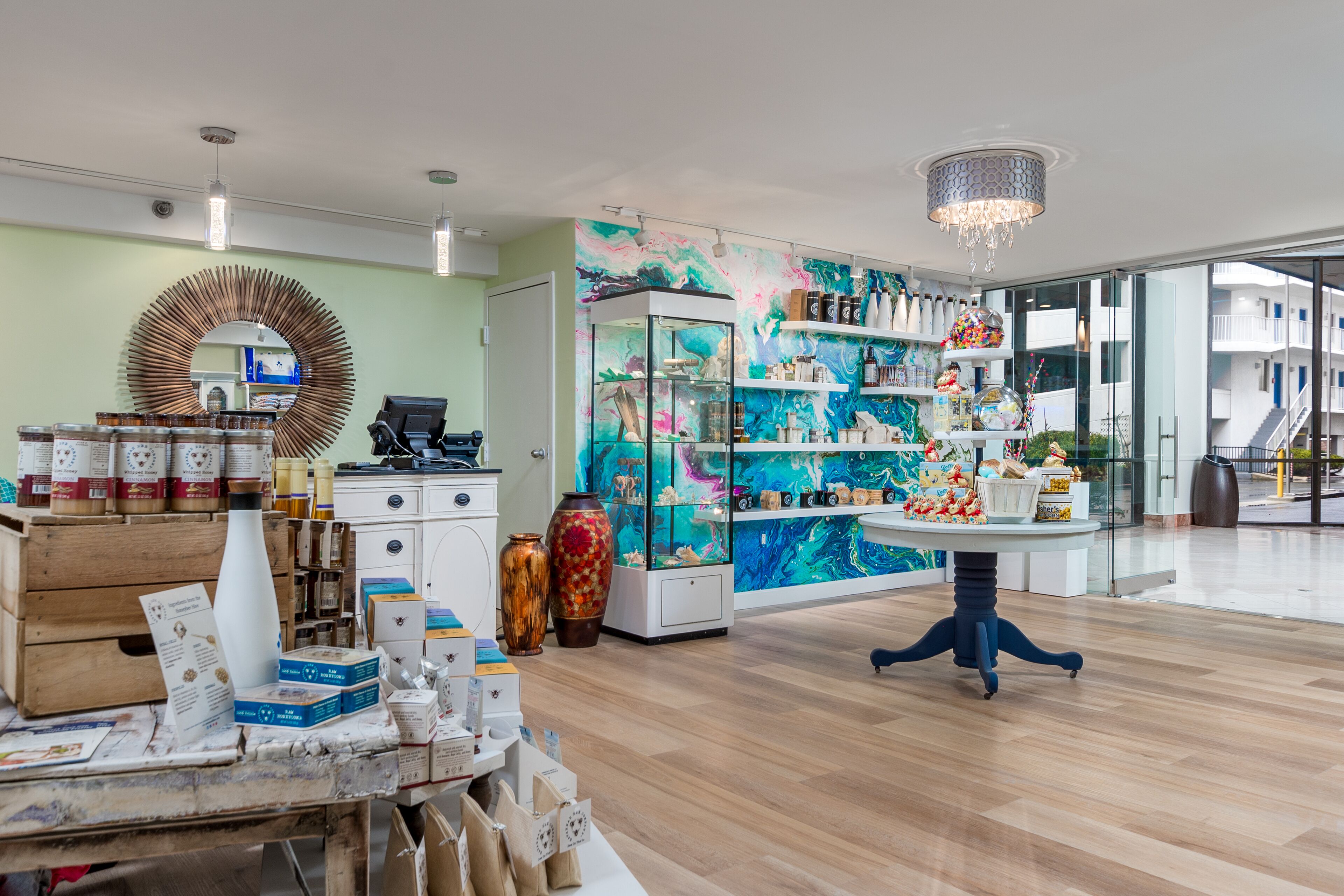Un intérieur moderne avec un plancher en bois, un grand miroir et une vitrine en verre remplie d’objets décoratifs.