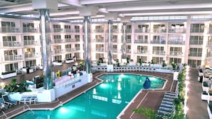 A multi-level hotel with a central pool area, multiple balconies, and indoor seating areas.