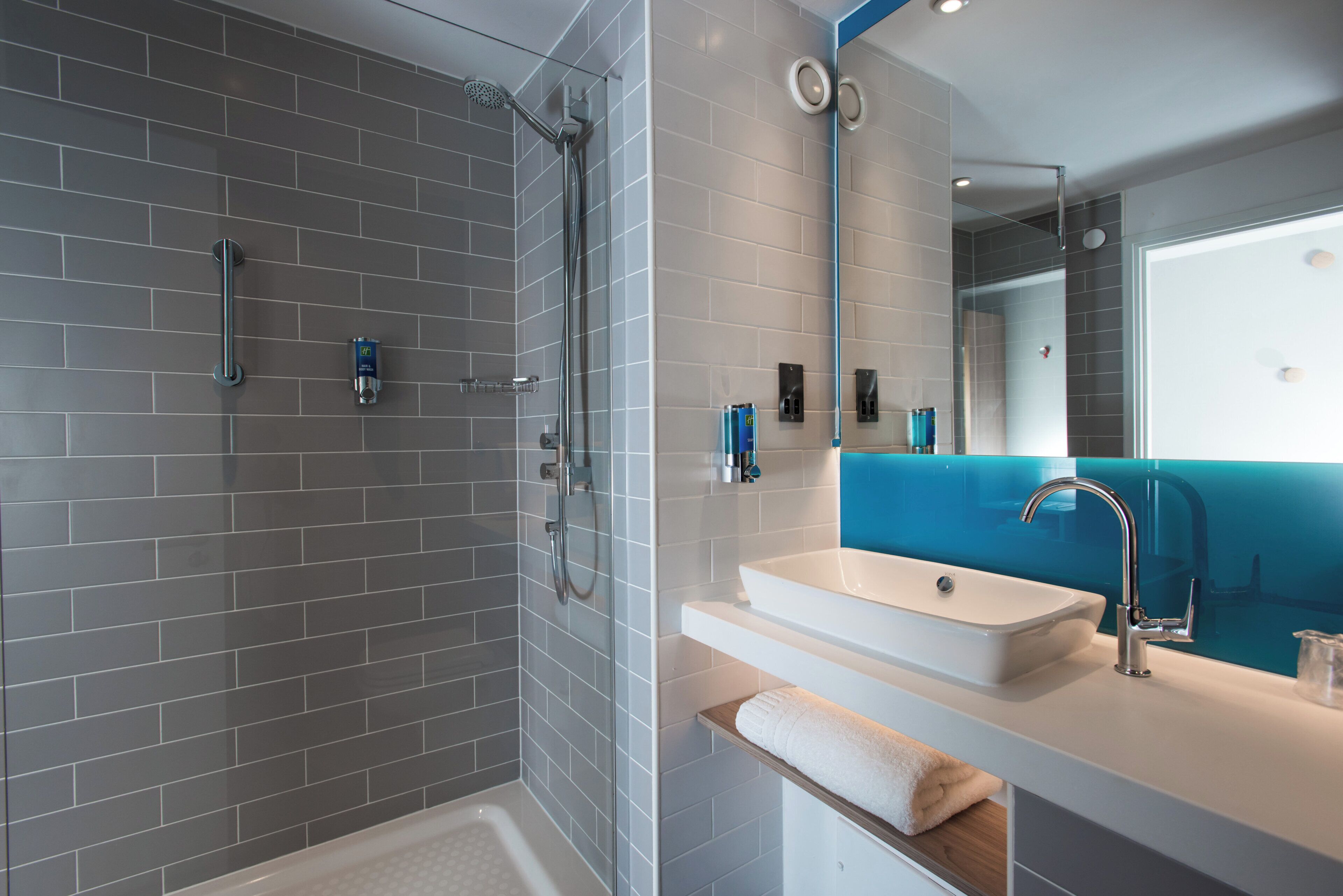 Une salle de bain moderne avec une douche, un lavabo et un miroir.