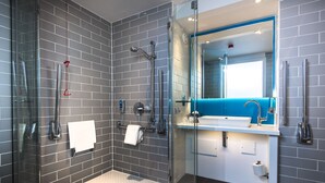 Un baño moderno con ducha de vidrio, un lavabo blanco y una pared de acento azul.