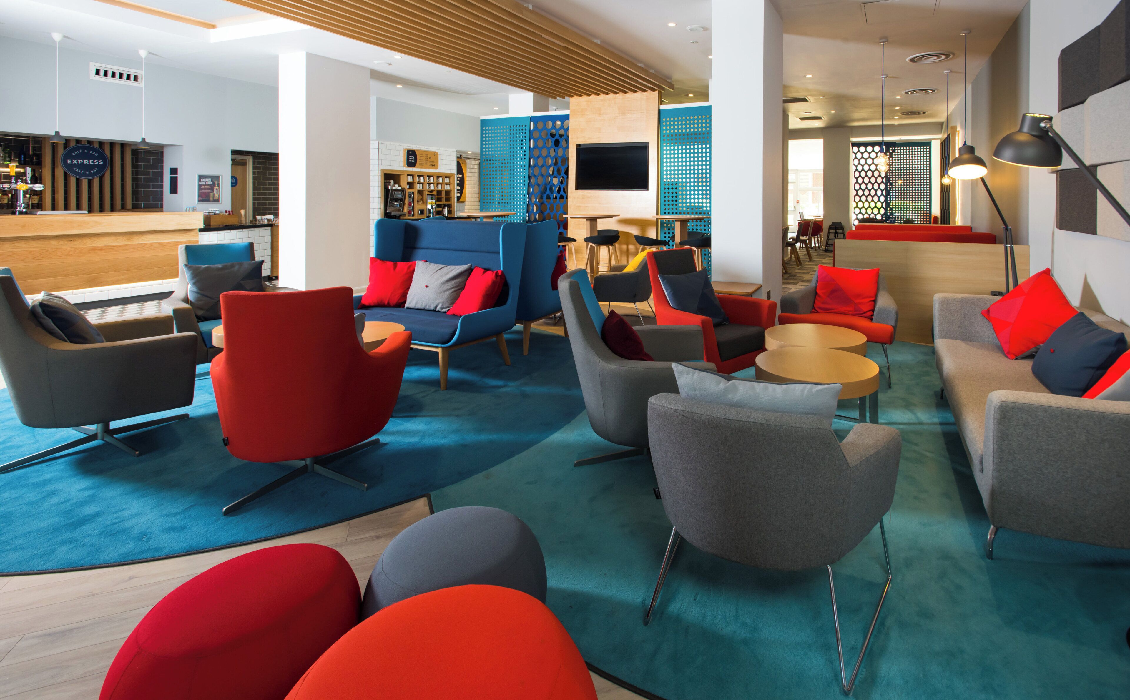 A modern lounge area with sofas and chairs, a reception desk, and a bar area.