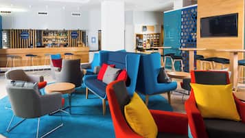 A modern lounge area with seating, a bar, and a coffee station.