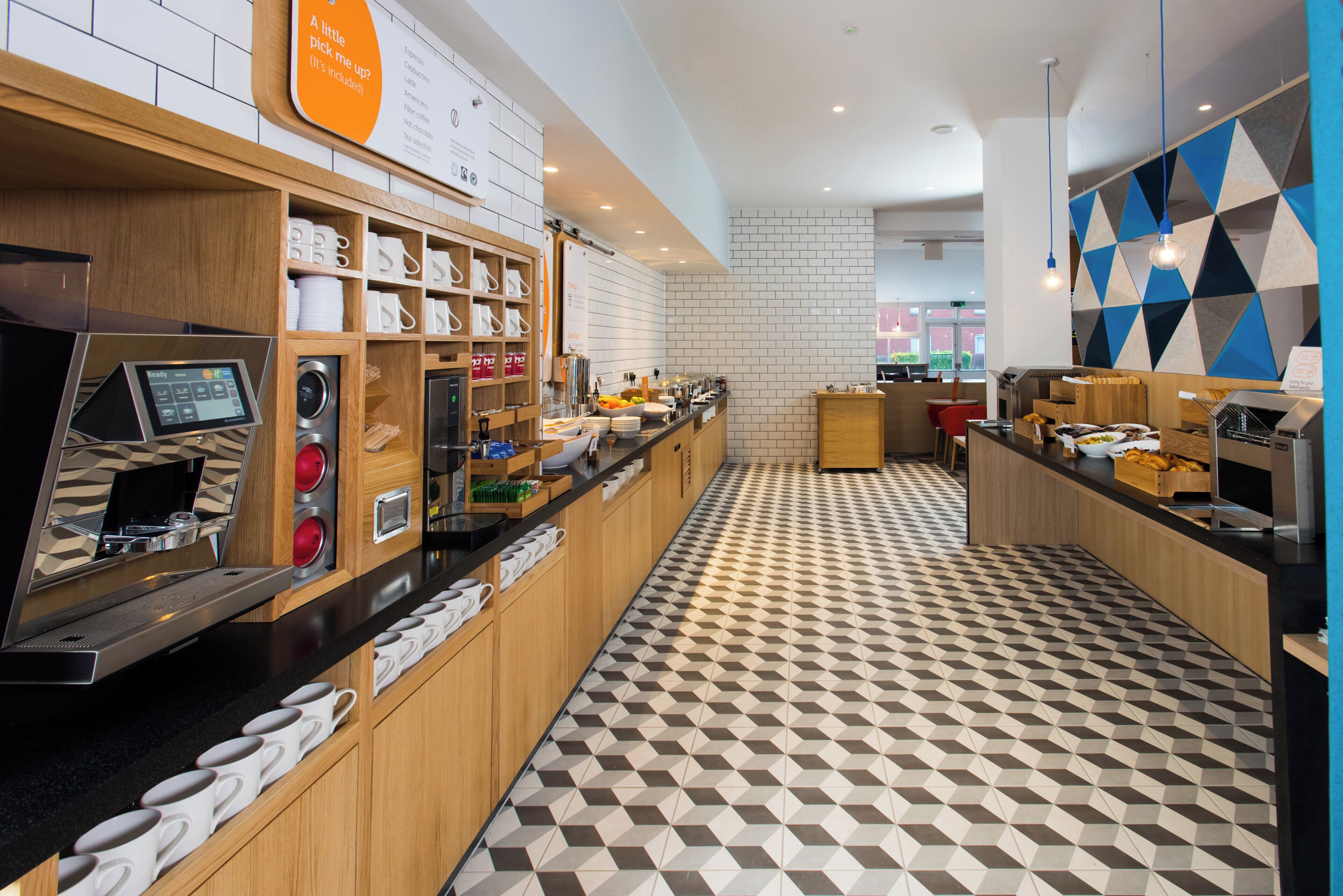 A modern coffee shop interior with a check-in kiosk, coffee machines, and a variety of coffee options displayed on the wall.