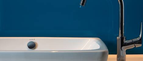 A modern bathroom with a white sink and a chrome faucet.