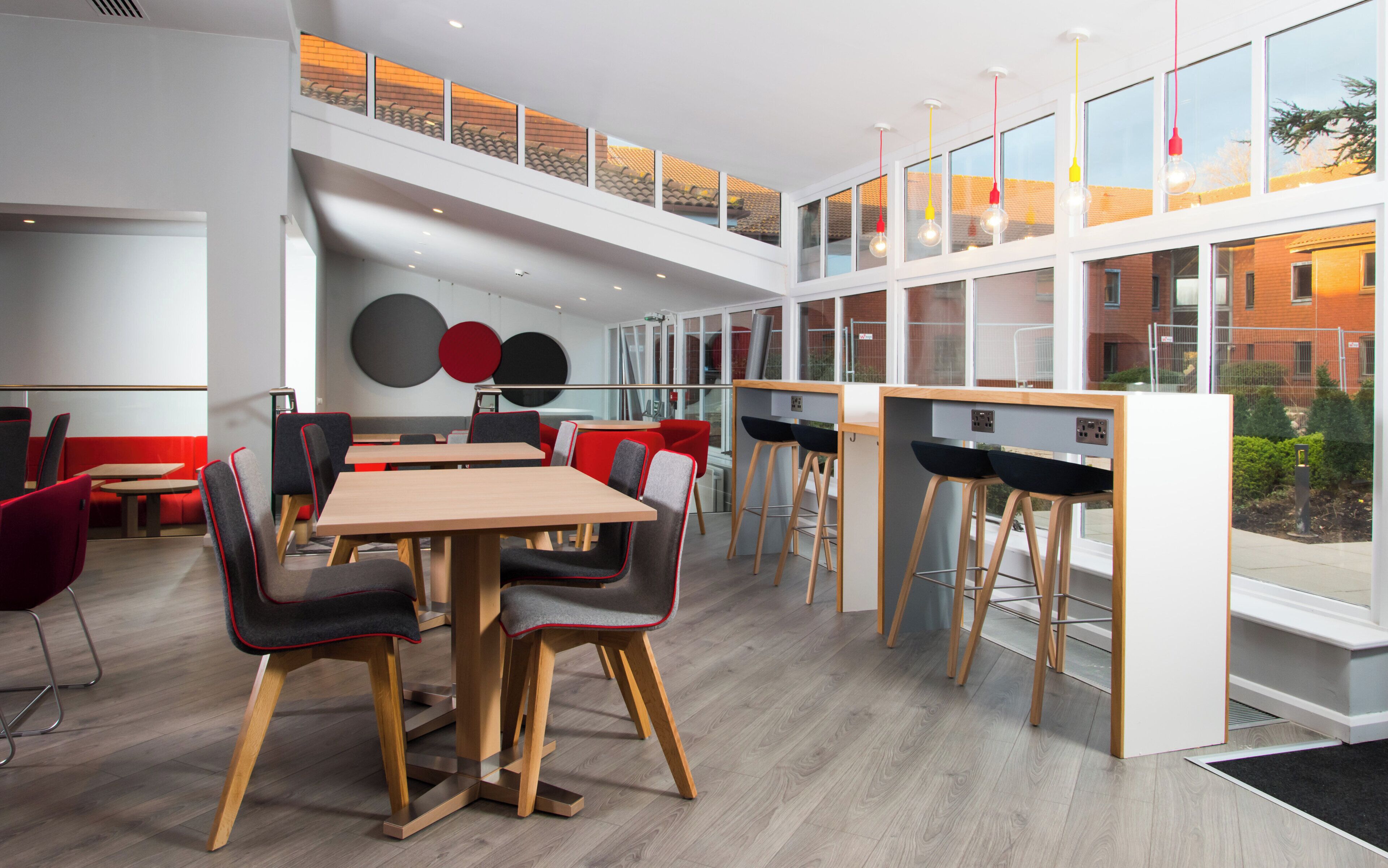 A modern dining area with a high ceiling, multiple tables, and chairs.