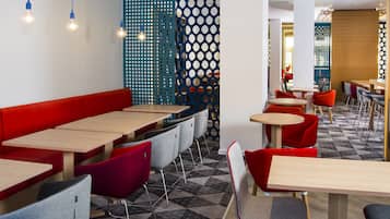 A modern restaurant with red and grey seating, wooden tables, and a patterned floor.