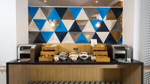 A breakfast bar with a geometric-patterned wall, a wooden counter, and a patterned floor. - Holiday Inn Express Portsmouth - North by IHG (Portsmouth)