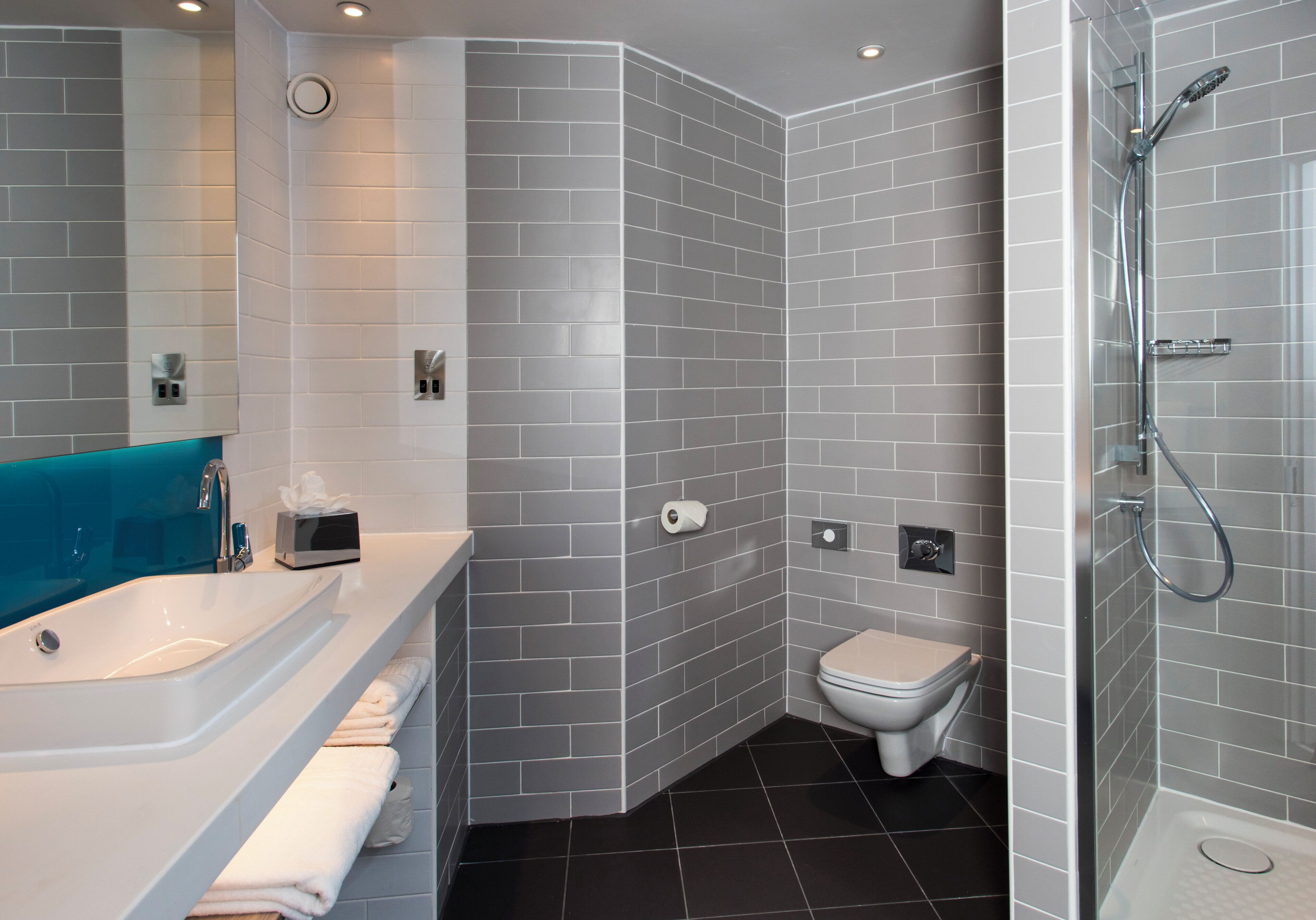 A modern bathroom with a white bathtub, a toilet, and a shower area.
