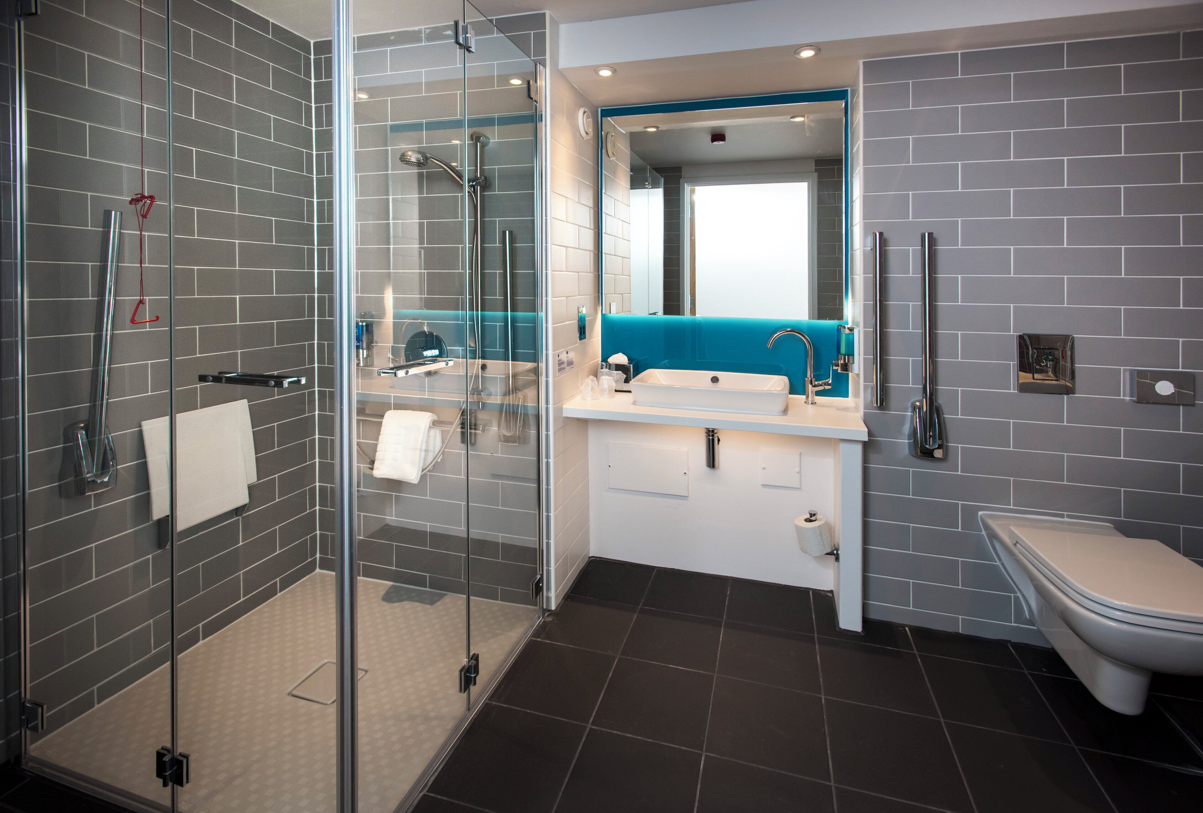 A modern bathroom with a glass-enclosed shower, a white sink with a blue accent, and a white toilet.