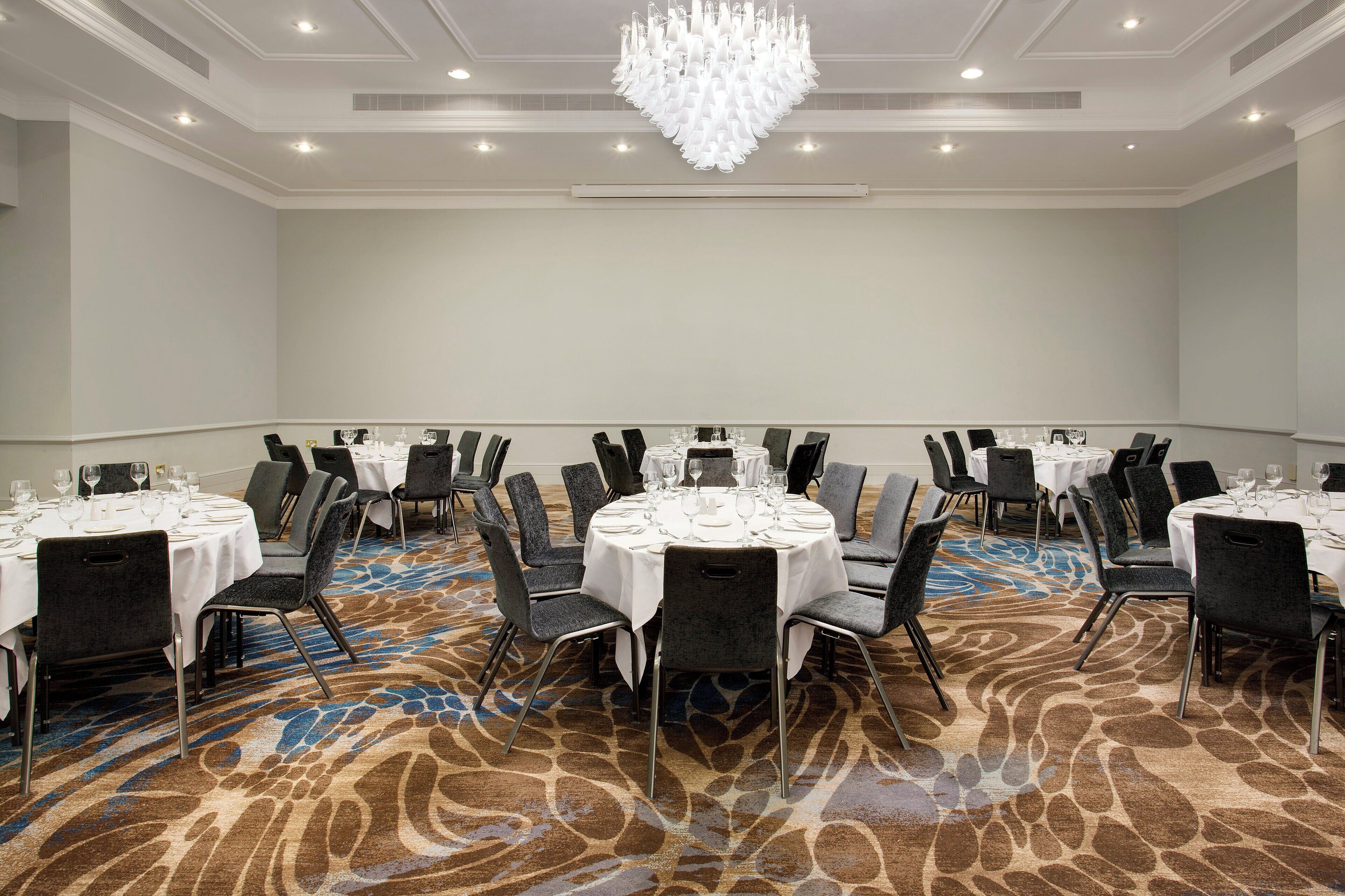 A conference room with round tables, chairs, and a chandelier.