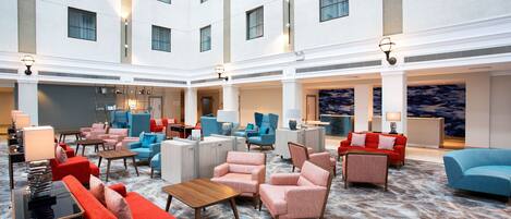 Un lobby amplio con varias zonas de estar, incluyendo sofás y sillones, y una mesa de centro.