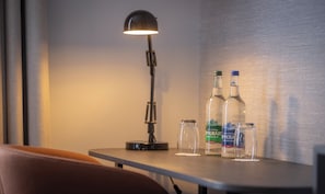 Una mesa con una lámpara y dos botellas de agua irlandesa.