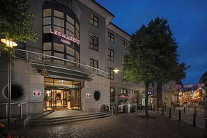 Entrada de un hotel con un letrero que dice 'LEONARDO HOTEL' y una escalera que conduce a la puerta.