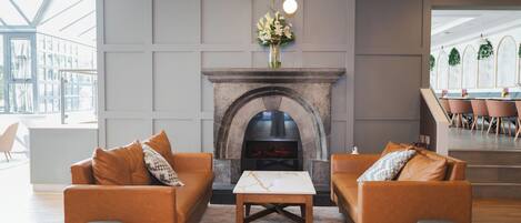 A modern living room with a fireplace, two sofas, a coffee table, and a large window.