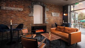 Cómoda sala de estar con chimenea de ladrillo, asientos de cuero y vistas al exterior.