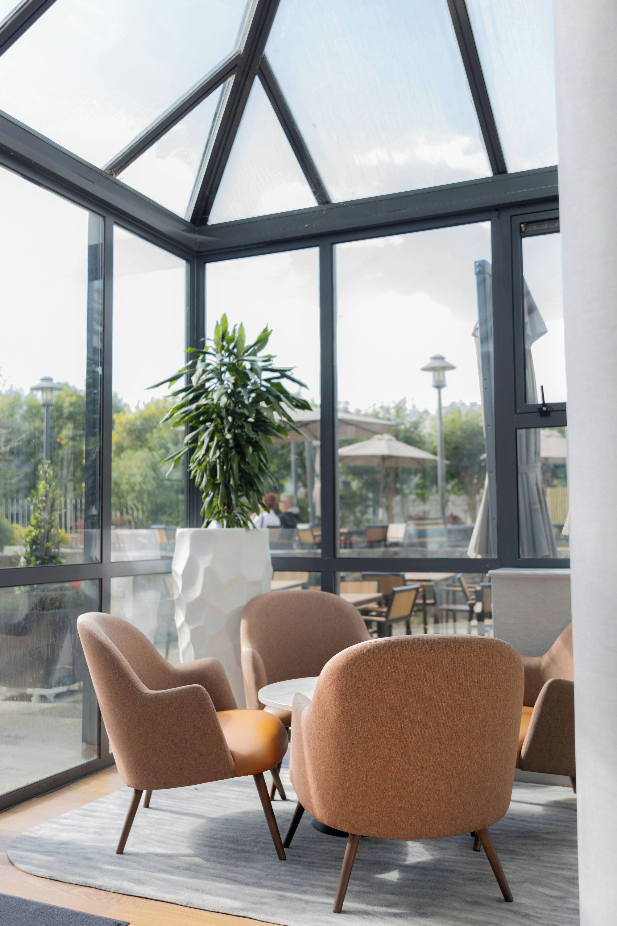 Een modern interieur met een glazen dak, een potplant en zithoekjes.