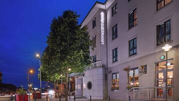 A hotel with a prominent sign, a well-lit entrance, and a visible staircase leading to the entrance.