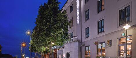 Et hotel med et tydeligt skilt, en godt oplyst indgang og en synlig trappe til indgangen.