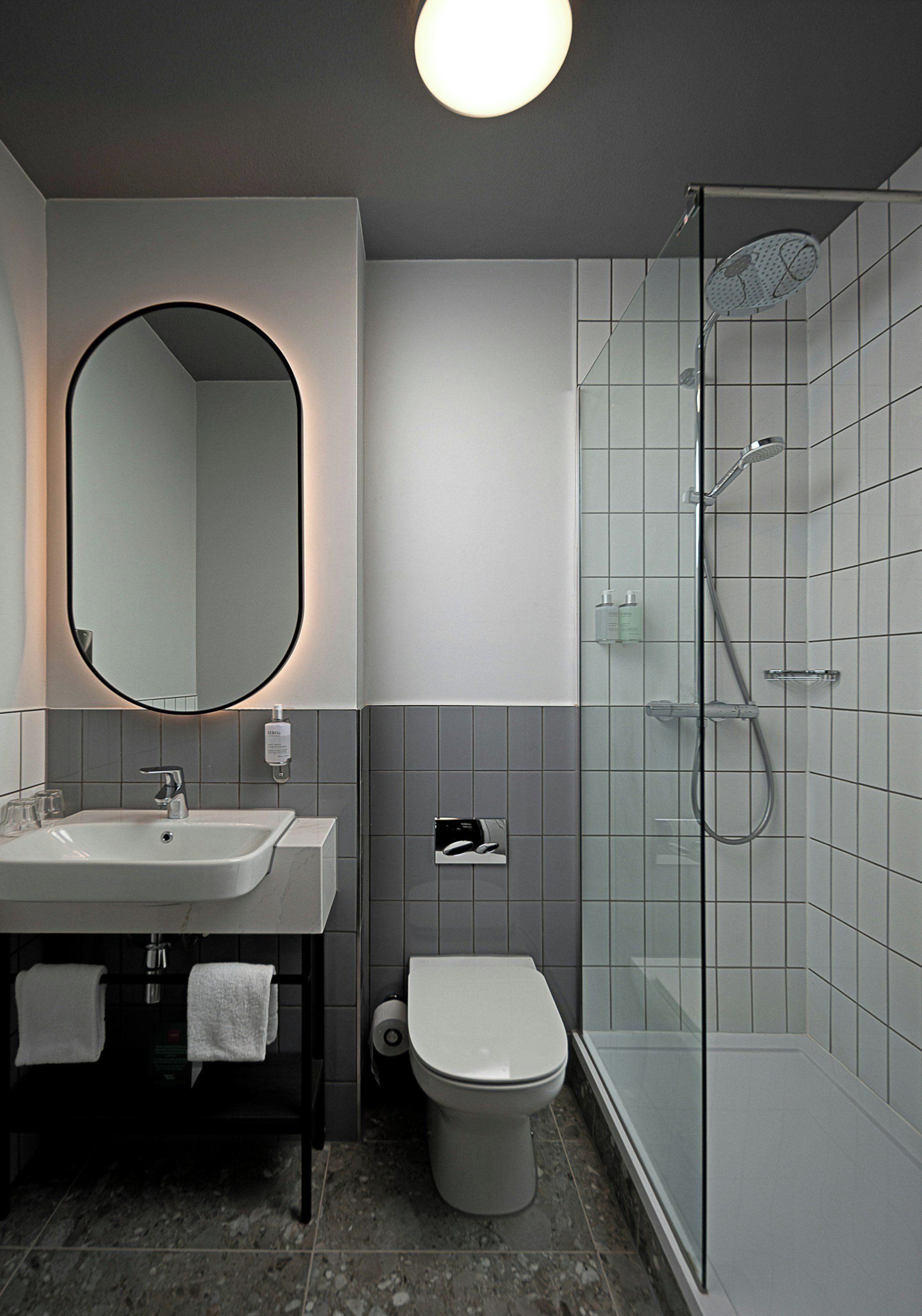A modern bathroom with a sink, mirror, toilet, and shower.