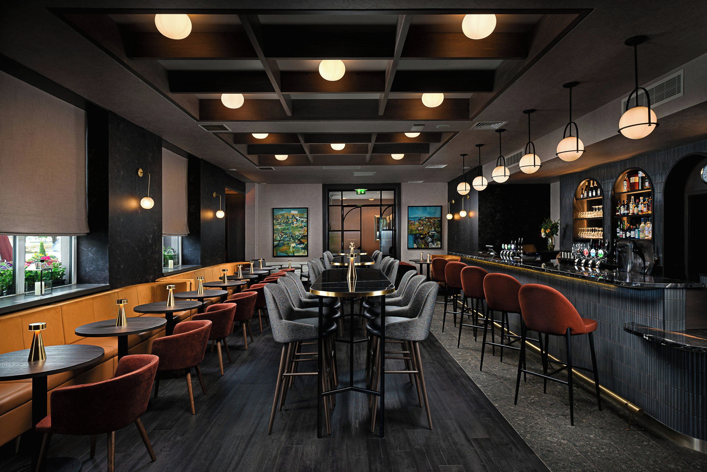 A bar area with multiple seating options, including tables and bar stools, and a bar counter with a variety of bottles.