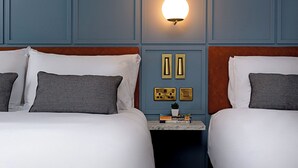 Habitació d'hotel amb dos llits, una tauleta de nit amb una làmpada i un lluminari fixat a la paret.