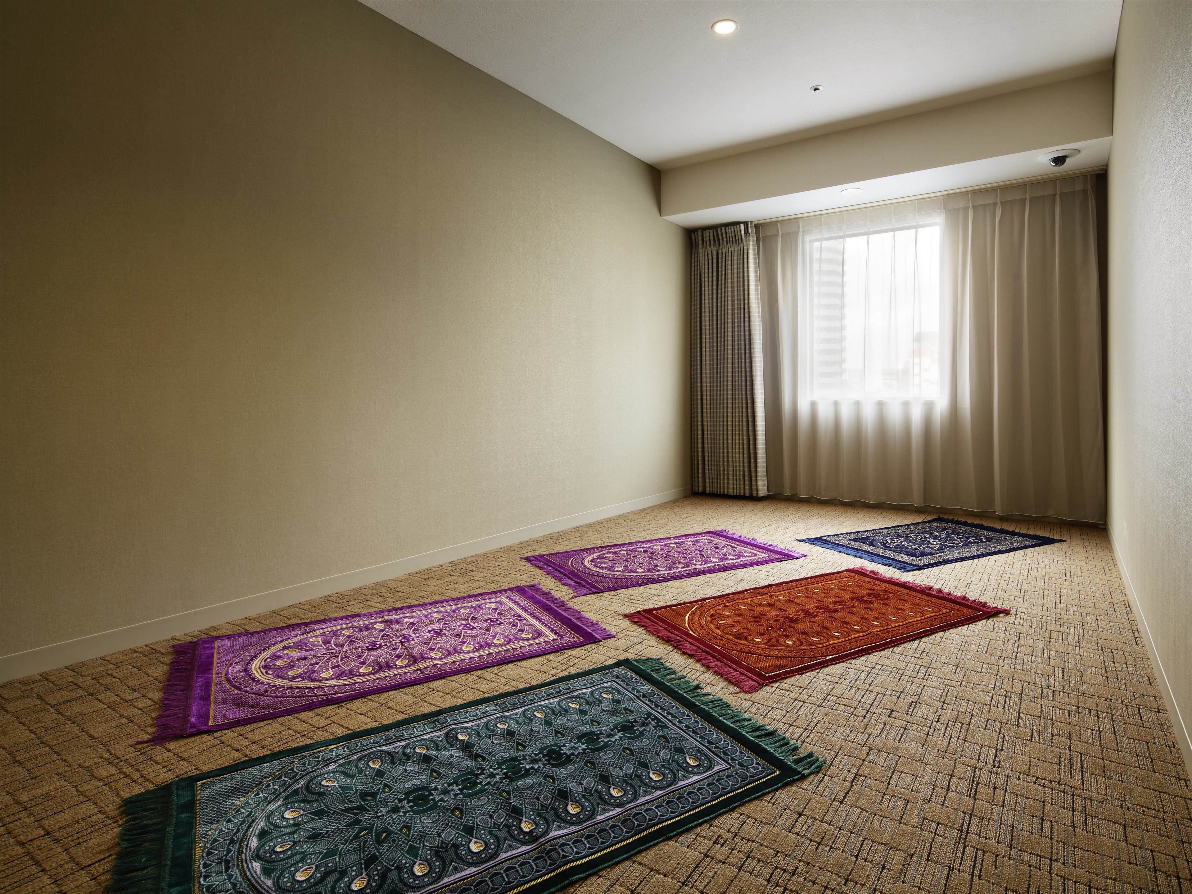 Una habitación con piso alfombrado, una ventana con cortinas y una lámpara en el techo.