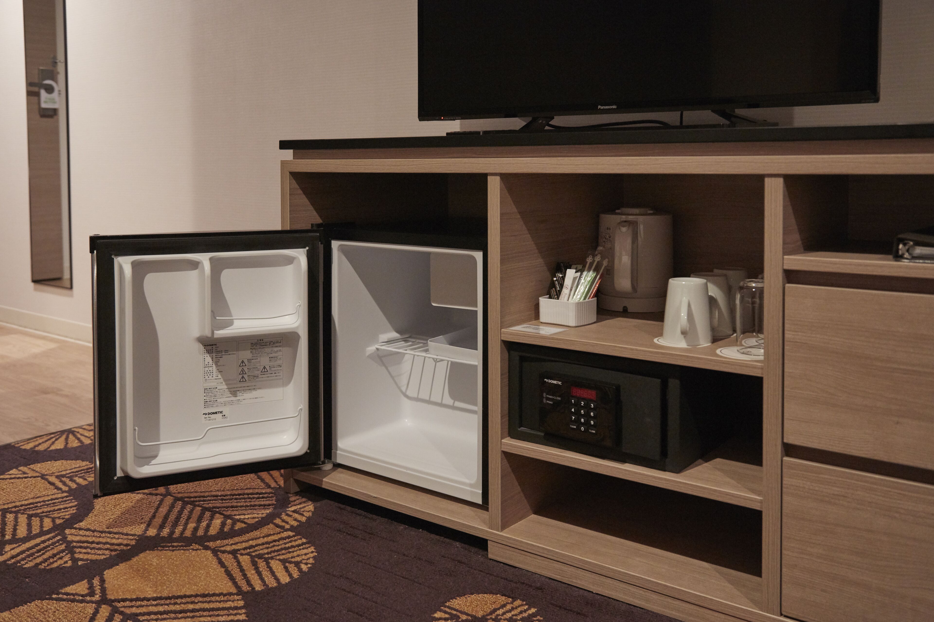 A hotel room with a built-in refrigerator, a television, and a coffee maker.