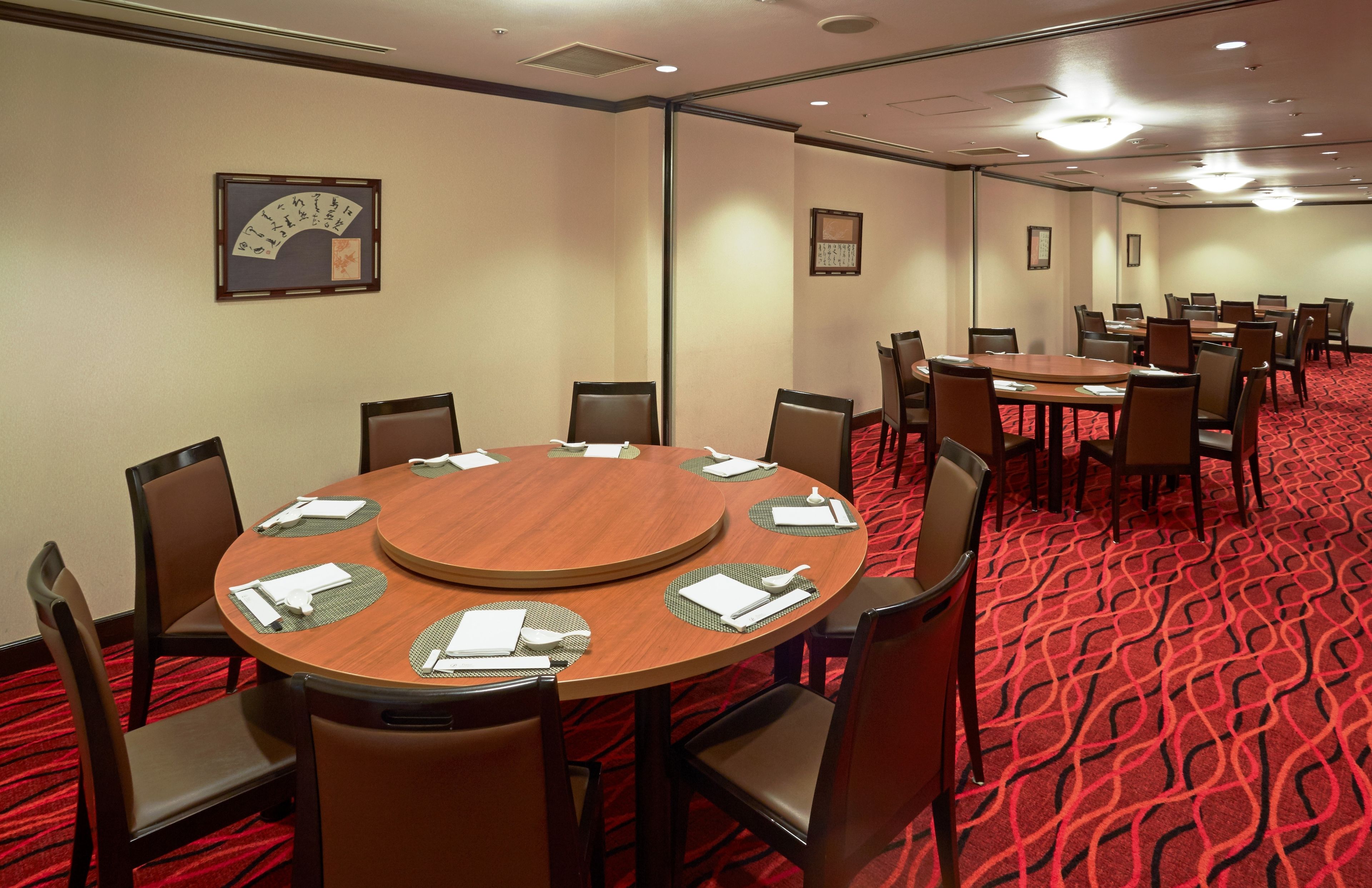 A conference room with round tables, chairs, and a red carpeted floor.