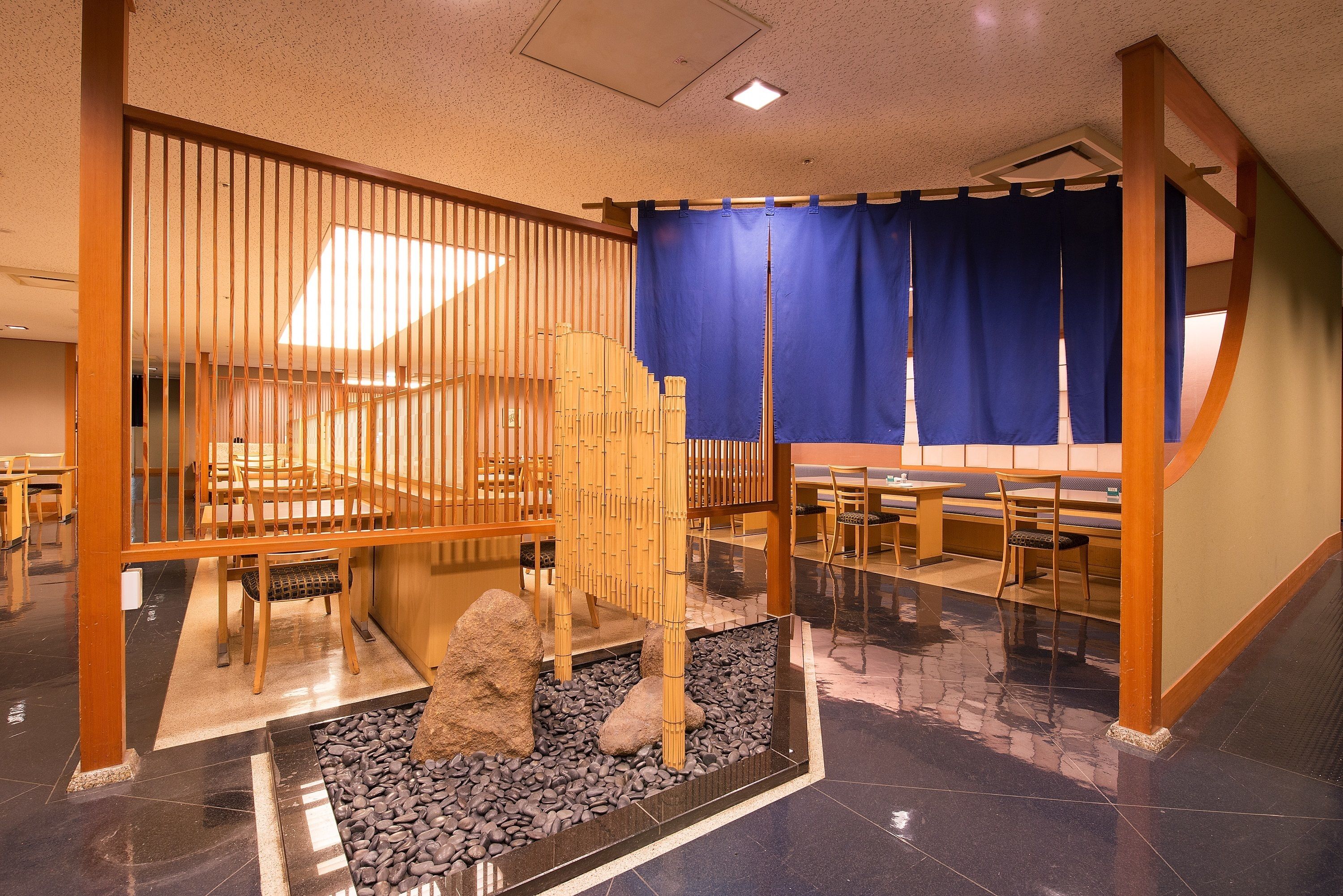 Una habitación tradicional japonesa con esteras de tatami, mesas de madera bajas y un panel divisor de shoji.